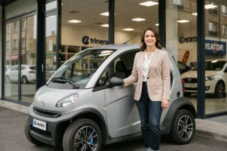 Femme en blazer beige à côté d'une voiture sans permis devant un showroom automobile moderne