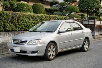 Toyota Corolla silver fiable garée dans une rue résidentielle japonaise, illustrant la longévité des voitures asiatiques